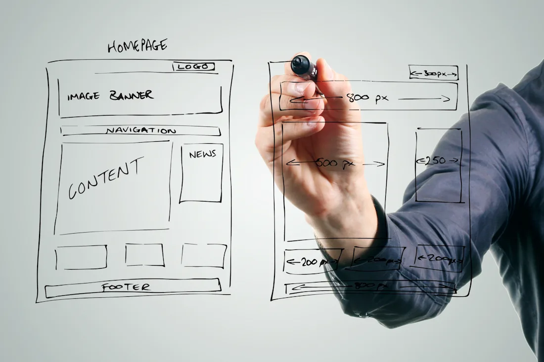 Planung und Konzeption einer Webseite: Ein Webdesigner skizziert ein Wireframe auf ein Glas-Whiteboard.